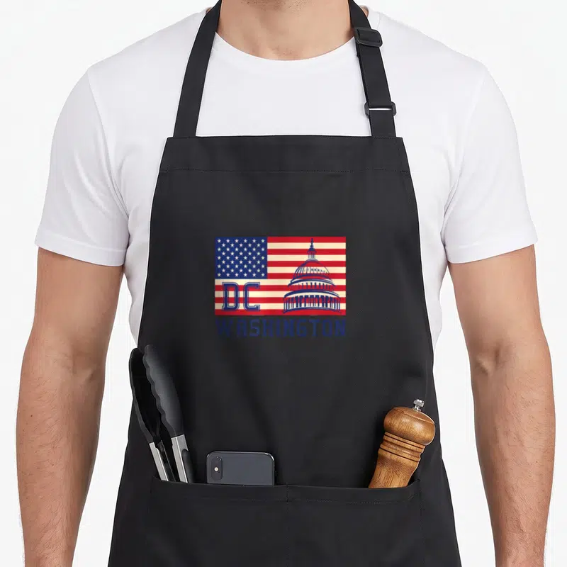 Tablier de cuisine noir avec un drapeau stylisé des États-Unis de Washington DC intégrant le Capitole et les lettres DC en bleu.