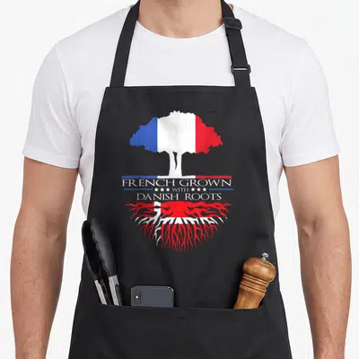 Tablier de cuisine noir avec un arbre aux drapeaux français et danois et le texte French Grown with Danish Roots.