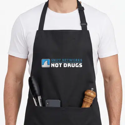 Tablier de cuisine noir avec logo Sniff Networks Not Drugs et aileron de shark blanc sur fond bleu.