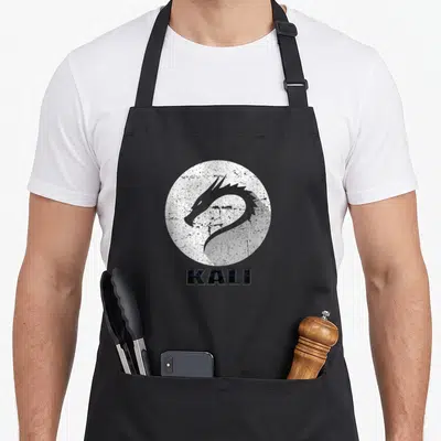 Tablier de cuisine noir avec logo tête de dragon Kali et texte texturé en bas du motif circulaire.