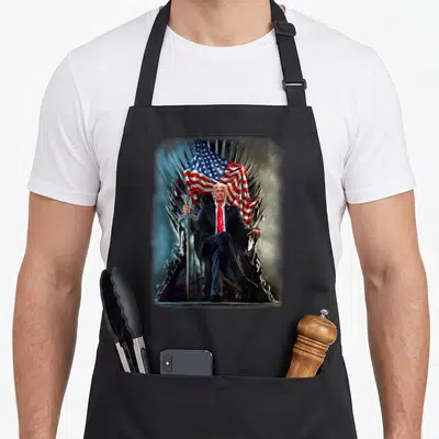 Tablier de cuisine noir avec Donald Trump assis sur un trône d'épées sous le drapeau américain.