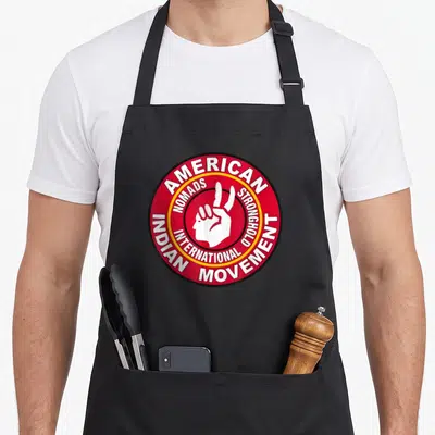 Tablier de cuisine noir avec un logo circulaire rouge portant la mention American Nomads Stronghold International.