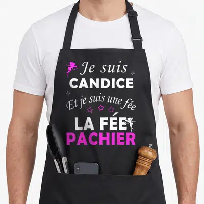 Tablier de cuisine noir avec le texte Je suis Candice et je suis une fée la fée pachier en blanc et rose vif.