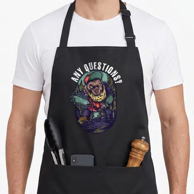 Tablier de cuisine noir avec illustration d'un gnome armé d'une tronçonneuse et du texte Any Questions au-dessus.