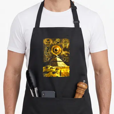 Tablier de cuisine noir avec illustration dorée de pyramides, œil d'Horus et chameaux dans le désert.