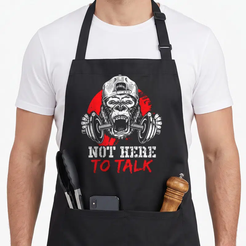 Tablier de cuisine noir avec illustration d'un gorille brandissant un barbell et le texte Not Here To Talk en blanc et rouge.