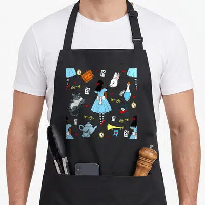 Tablier de cuisine noir avec Alice au pays des merveilles gribouillis, lapin, chat et cartes à jouer.