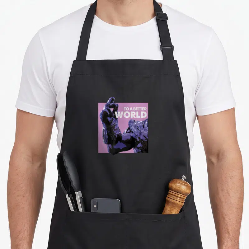 Tablier de cuisine noir avec illustration d'une main gantée violet foncé et texte TO A BETTER WORLD sur fond rose.