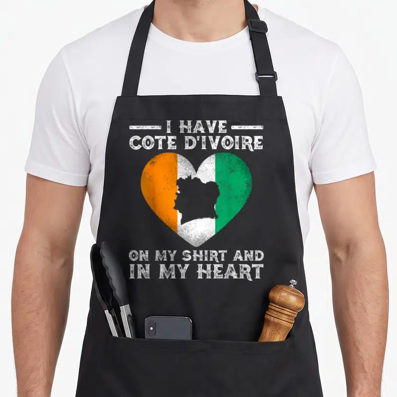 Tablier de cuisine noir avec un cœur aux couleurs orange blanc vert contenant la carte de la Côte d'Ivoire et du texte en anglais.