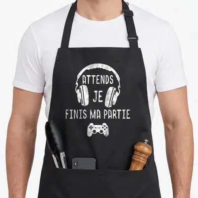 Tablier de cuisine noir avec illustration blanche d'un casque audio et d'une manette de jeu