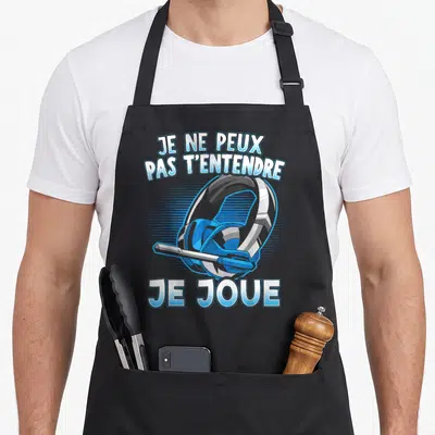 Tablier de cuisine noir avec illustration de casque gamer et texte Je ne peux pas t'entendre je joue en lettres bleues.