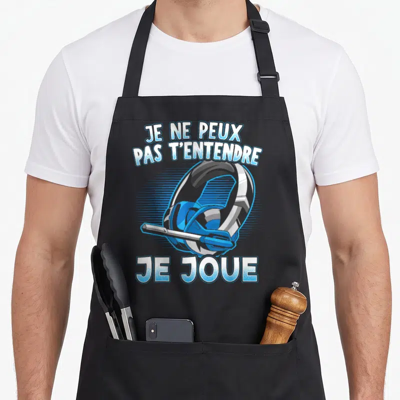 Tablier de cuisine noir avec illustration de casque gamer et texte Je ne peux pas t'entendre je joue en lettres bleues.