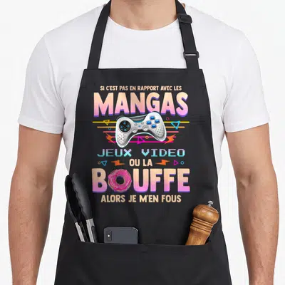 Tablier de cuisine noir avec manette de jeu, donut rose et texte humoristique sur mangas et jeux vidéo.