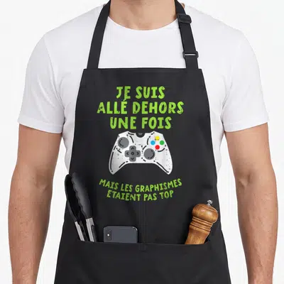 Tablier de cuisine noir avec une manette de jeu blanche et texte vert sur le thème des graphismes.