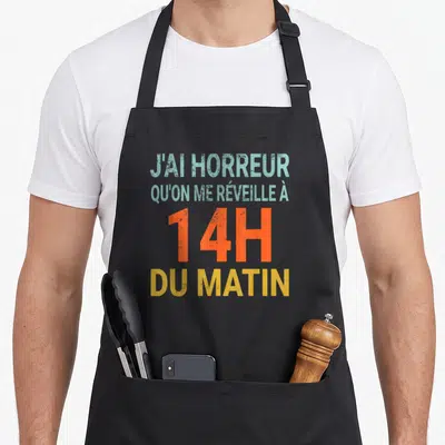 Tablier de cuisine noir avec le texte J'ai horreur qu'on me réveille à 14h du matin en typographie colorée et dégradée.