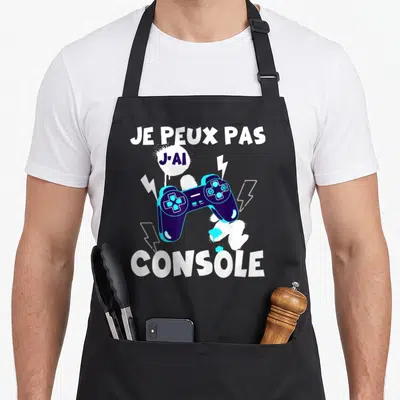 Tablier de cuisine noir avec une manette de jeu vidéo et le texte Je peux pas j'ai console imprimé en blanc et bleu.