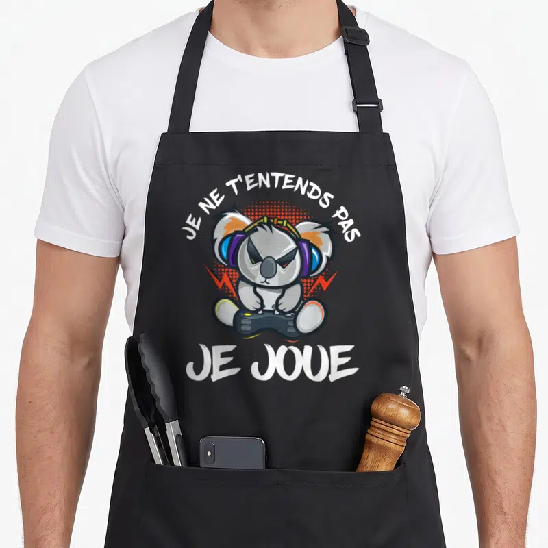 Tablier de cuisine noir avec illustration d'un koala portant des écouteurs et tenant une manette sous le texte Je ne t'entends pas je joue.