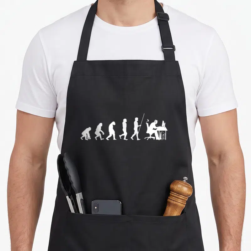 Tablier de cuisine noir avec illustration blanche montrant l'évolution humaine se terminant par un gamer au bureau.
