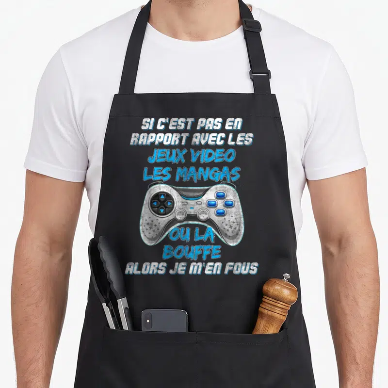 Tablier de cuisine noir avec une illustration de manette de jeu vidéo et un texte humoristique sur les passions gaming et manga.