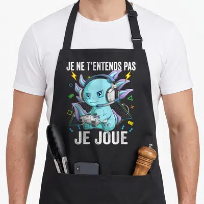 Tablier de cuisine noir avec un axolotl bleu gamer portant des écouteurs et tenant une manette de jeu vidéo.