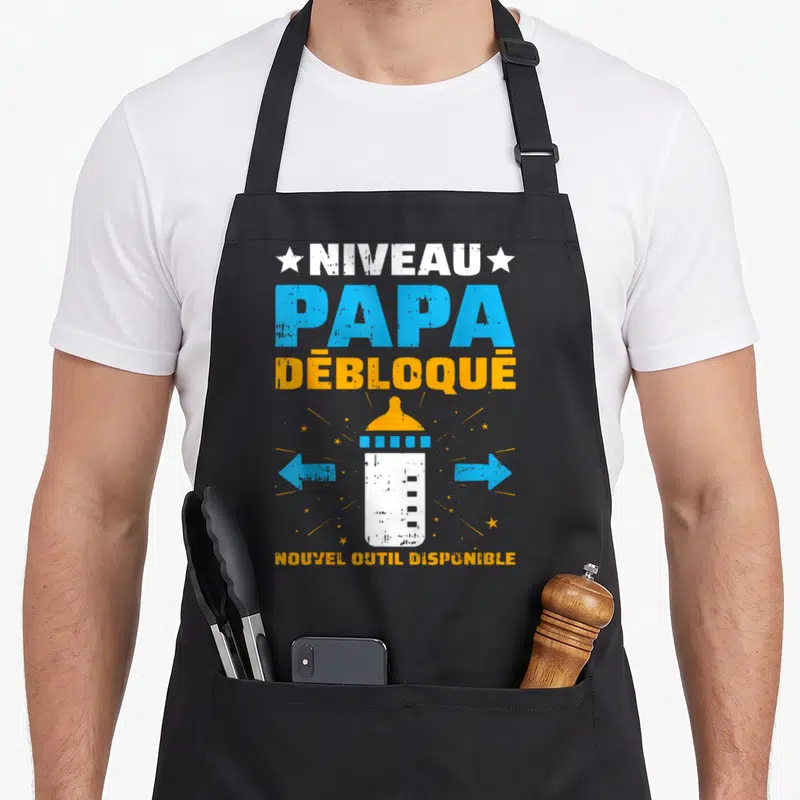 Tablier de cuisine noir avec illustration biberon niveau papa débloqué et flèches bleues directionnelles.
