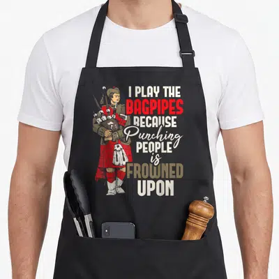 Tablier de cuisine noir avec illustration d'un joueur de cornemuse et texte anglais humoristique en rouge et blanc.