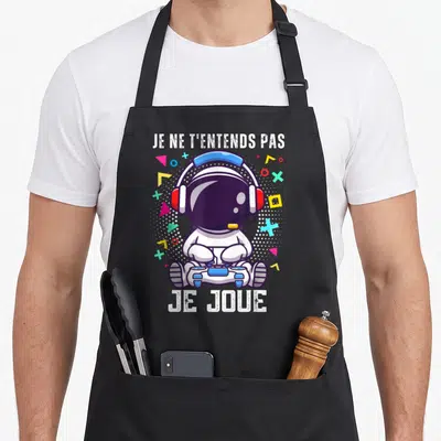Tablier de cuisine noir avec illustration d'un astronaute tenant une manette et le texte Je ne t'entends pas je joue.
