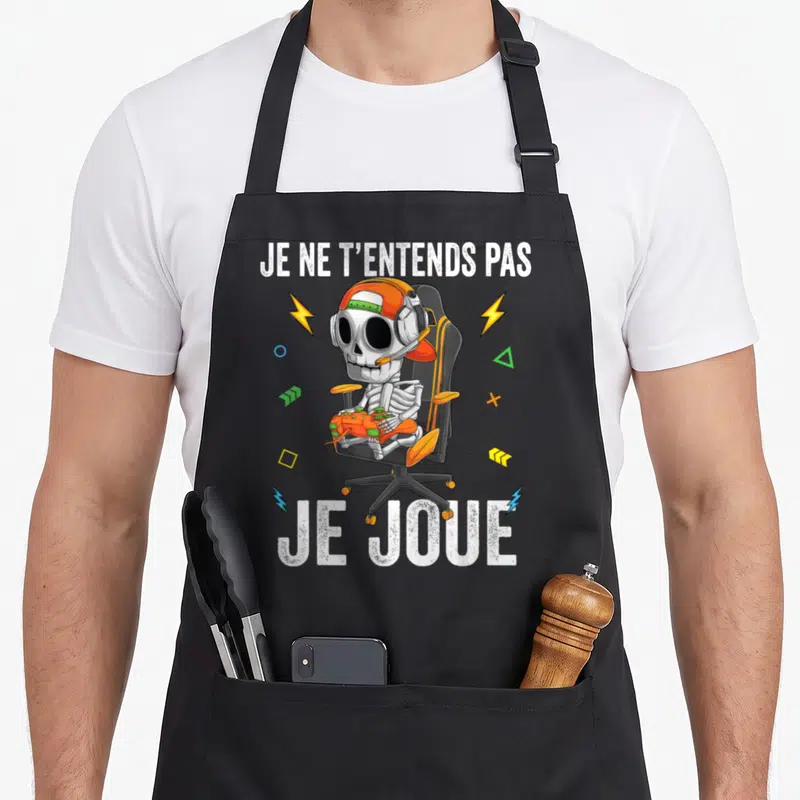 Tablier de cuisine noir avec un squelette gamer et l'inscription Je ne t'entends pas je joue.