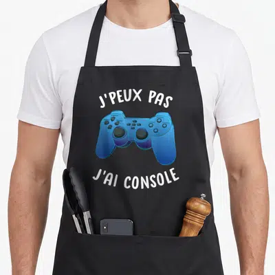 Tablier de cuisine noir avec une illustration de manette de jeu vidéo bleue et du texte blanc.