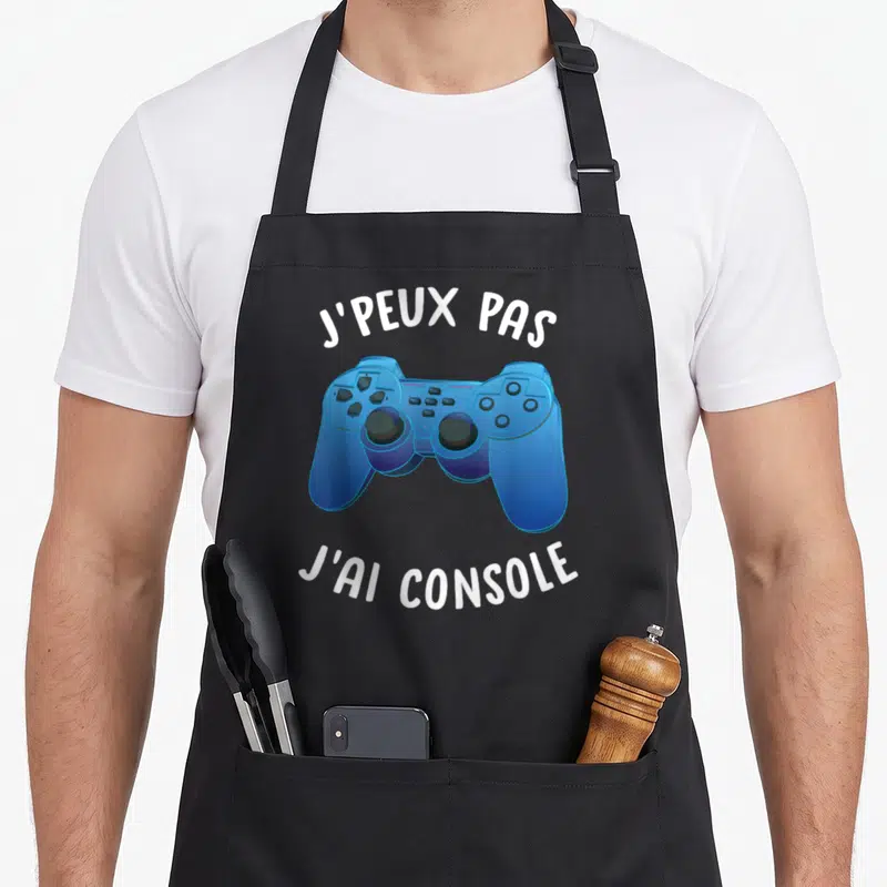 Tablier de cuisine noir avec une illustration de manette de jeu vidéo bleue et du texte blanc.