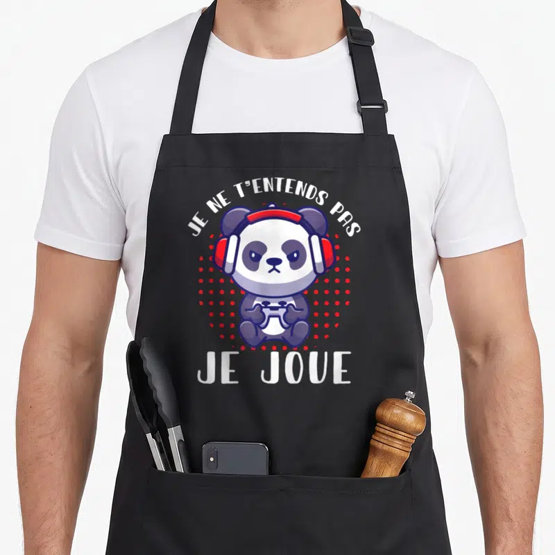 Tablier de cuisine noir avec un panda gamer aux écouteurs rouges tenant une manette blanche au centre du motif.