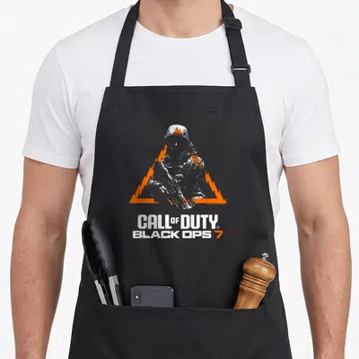 Tablier de cuisine noir avec silhouette militaire, triangle orange et texte Call of Duty Black Ops 7 imprimé.
