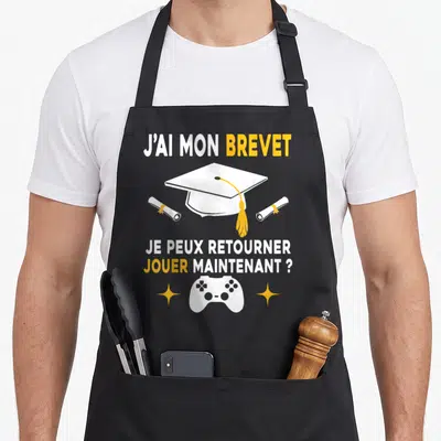 Tablier de cuisine noir avec inscription J'ai mon brevet et illustration de manette de jeu vidéo blanche et jaune.