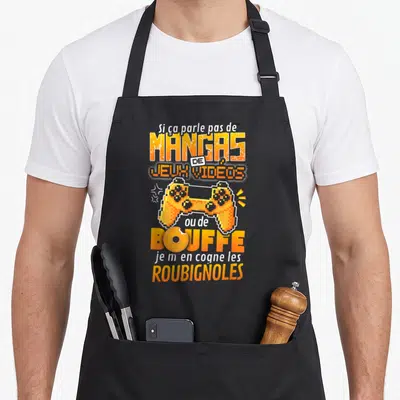 Tablier de cuisine noir avec une manette orange pixelisée et un texte humoristique sur les mangas et la bouffe.