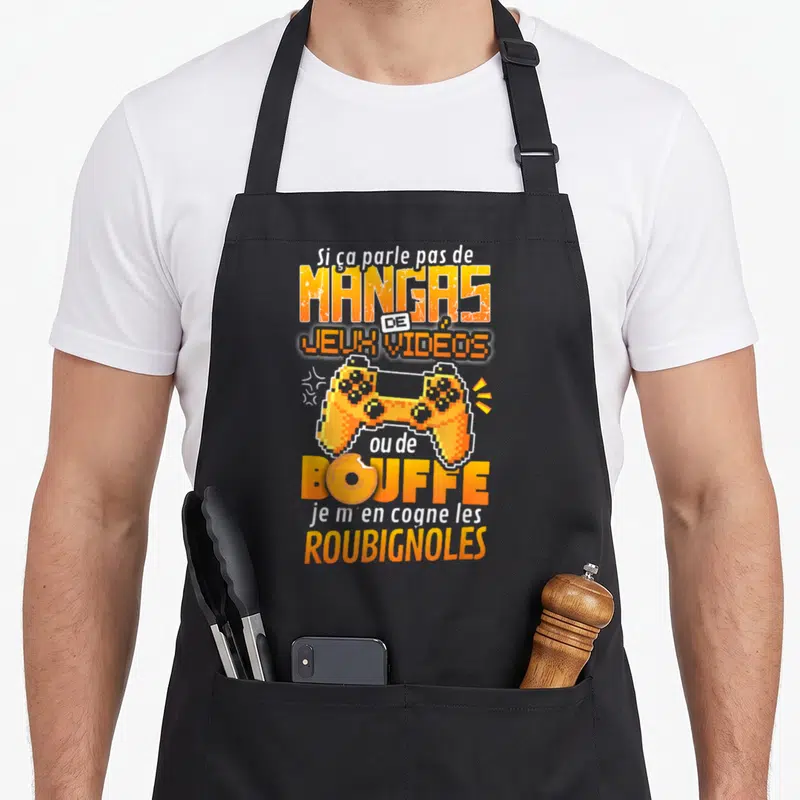 Tablier de cuisine noir avec une manette orange pixelisée et un texte humoristique sur les mangas et la bouffe.