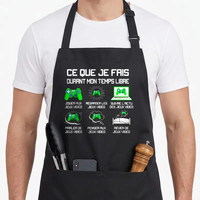 Tablier de cuisine noir avec texte blanc et illustrations vertes de manettes de jeu vidéo et d'un ordinateur portable.
