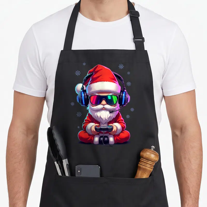 Tablier de cuisine noir avec illustration d'un Père Noël Gamer portant des lunettes de soleil et un casque audio.