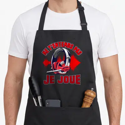Tablier de cuisine noir avec illustration casque audio rouge et texte Ne t'entends pas je joue en lettres capitales rouges.