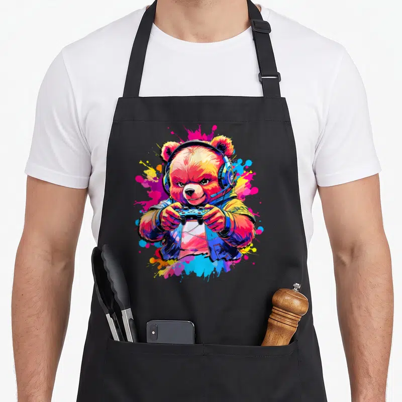 Tablier de cuisine noir avec illustration colorée d'un ours gamer portant un casque et tenant une manette.