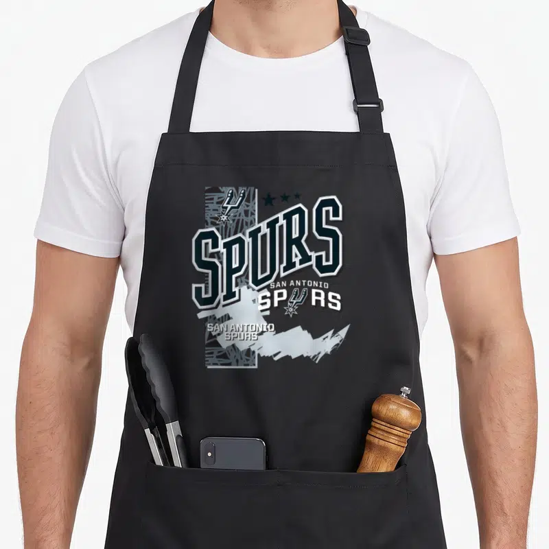 Tablier de cuisine noir avec inscription Spurs San Antonio et motifs graphiques en bleu marine et blanc sur fond texturé.