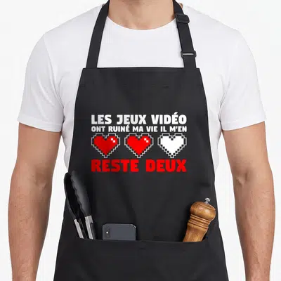 Tablier de cuisine noir avec inscription Les jeux vidéo ont ruiné ma vie et trois cœurs pixelisés rouges et blancs.