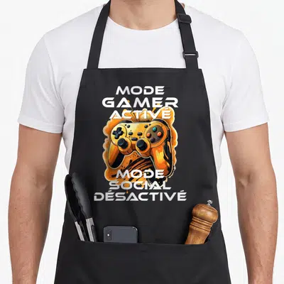 Tablier de cuisine noir avec une manette de jeu orange et les textes Mode Gamer Activé et Mode Social Désactivé en blanc.