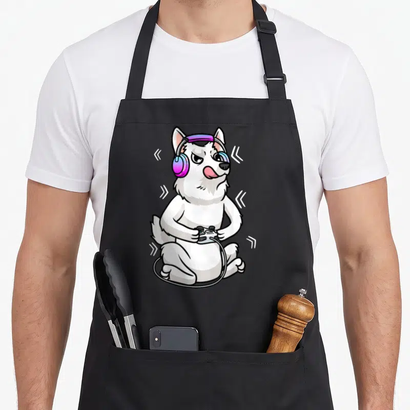 Tablier de cuisine noir avec illustration d'un Berger Blanc Suisse gamer aux écouteurs roses et manette noire.