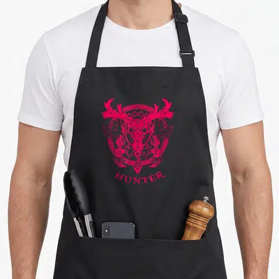 Tablier de cuisine noir avec emblème rose vif représentant un crâne de cerf aux bois imposants et le mot HUNTER en bas.