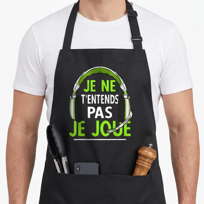 Tablier de cuisine noir avec illustration de casque gaming vert et blanc et texte humoristique sur le front.