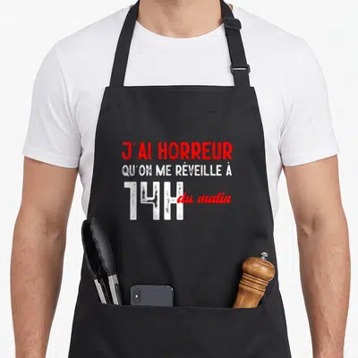 Tablier de cuisine noir avec l'inscription J'ai horreur qu'on me réveille à 14h du matin en lettres rouges et blanches.