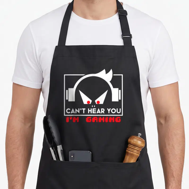 Tablier de cuisine noir avec illustration d'un personnage aux yeux rouges et casque blanc, texte en anglais.