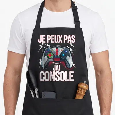 Tablier de cuisine noir avec illustration de manette de jeu et texte Je peux pas j'ai console entouré d'éclairs.