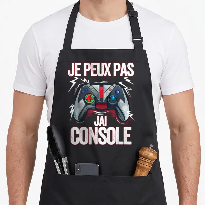 Tablier de cuisine noir avec illustration de manette de jeu et texte Je peux pas j'ai console entouré d'éclairs.