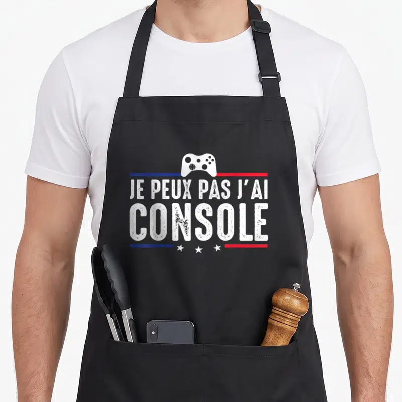 Tablier de cuisine noir avec inscription Je peux pas j'ai console et une manette de jeu vidéo blanche au centre.